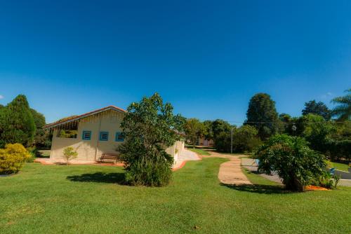 a house with a grassy yard next to a building at Hotel Alto da Boa Vista in Analândia