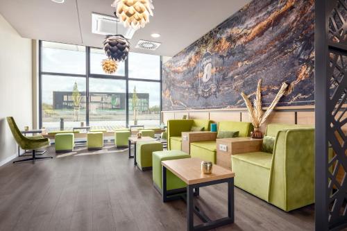 a lobby with green chairs and tables and a large mural at Super 8 by Wyndham Oberhausen am Centro in Oberhausen