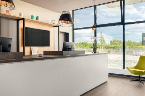 a kitchen with a television and a yellow chair at Super 8 by Wyndham Oberhausen am Centro in Oberhausen