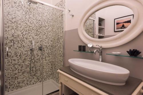 錫羅洛的住宿－Tra gli Alberi e il Mare，浴室配有盥洗盆和带镜子的淋浴