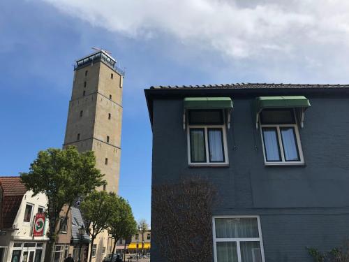 a building with a tower next to a building at Hotel Nap in West-Terschelling