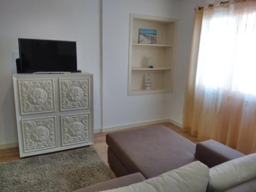 a living room with a couch and a tv on a cabinet at Sweet Dreams near Beaches in Ponta Delgada