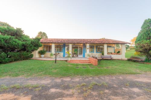 a house with a bench and a grass yard at Hotel Alto da Boa Vista in Analândia