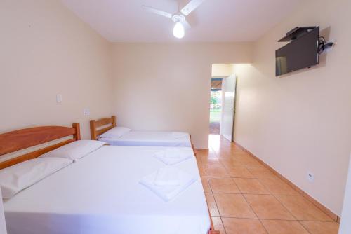 a bedroom with two beds and a flat screen tv at Hotel Alto da Boa Vista in Analândia