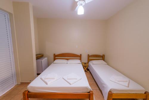 two twin beds in a room with a window at Hotel Alto da Boa Vista in Analândia