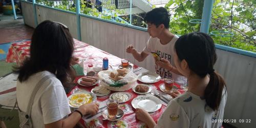 een groep mensen die rond een tafel eten bij Canal Hostel in Sheki
