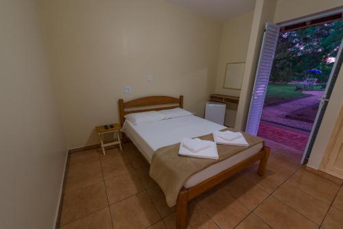 a bedroom with a bed and a door to a yard at Hotel Alto da Boa Vista in Analândia