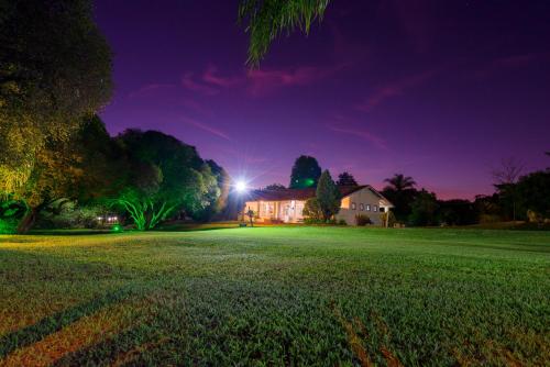 a house at night with a green field in front at Hotel Alto da Boa Vista in Analândia