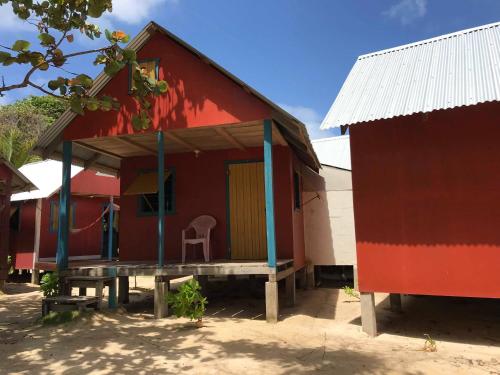 a red house with a chair in front of it at Sunrise Paradise/Carlito´s Place in Corn Island