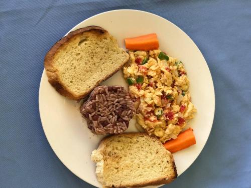 einen Teller mit Fleisch, Reis und Brot in der Unterkunft Sunrise Paradise/Carlito´s Place in Corn Island