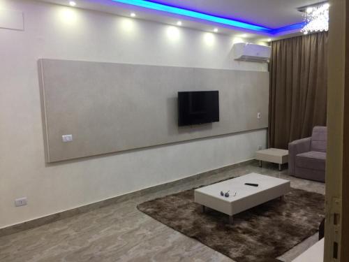 een woonkamer met een bank en een tv aan de muur bij Milsaa Studio in Caïro