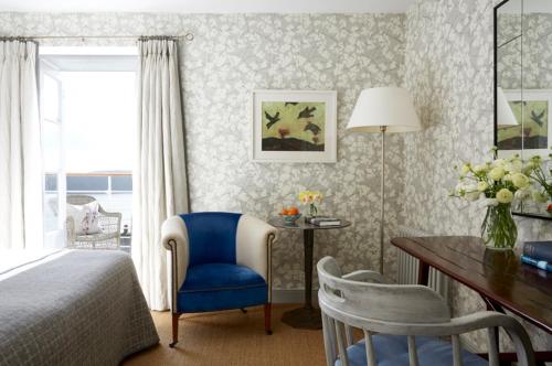 a bedroom with a bed and a desk and a blue chair at Hotel Tresanton in Saint Mawes