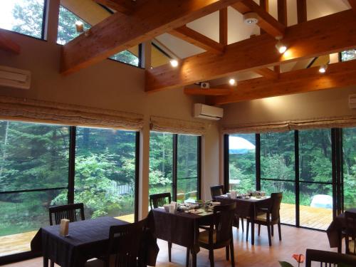 a dining room with tables and chairs and large windows at B&B Hotel Hyochoan in Karuizawa