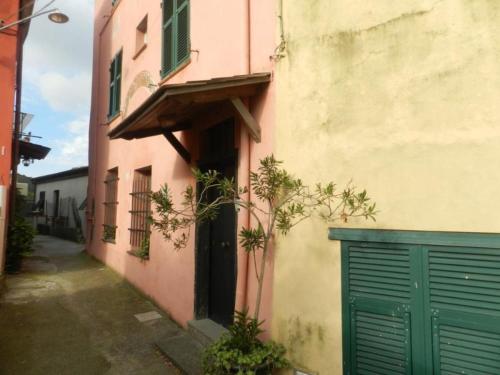 a pink building with a green door and a gate at Trilocale in dimora tipica in Montale