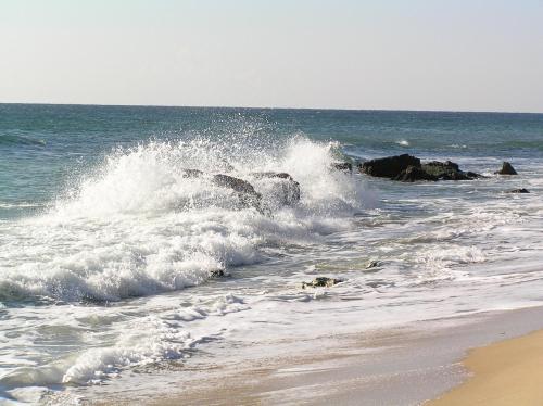 a wave breaking on a beach with rocks in the ocean at Morski Briag Hotel in Golden Sands