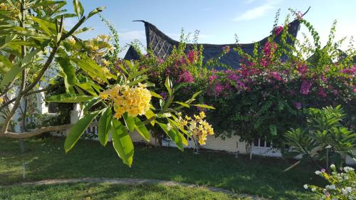 a garden with colorful flowers and a house at Princess of Mentigi Bay in Teluk Nara