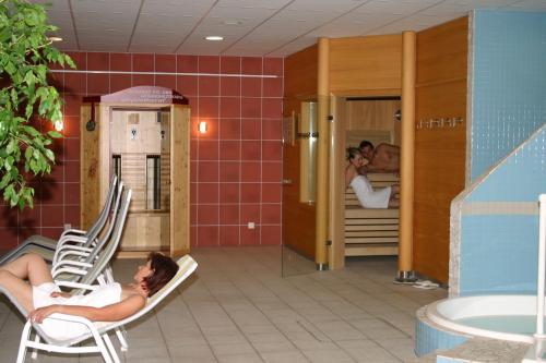 a woman laying in chairs in a room with beds at Joglland Hotel Prettenhofer in Wenigzell