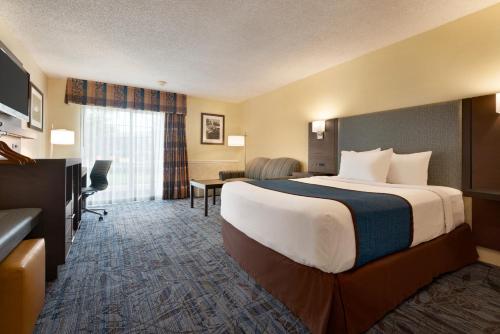 a hotel room with a large bed and a desk at Ramada by Wyndham Spokane Airport in Spokane