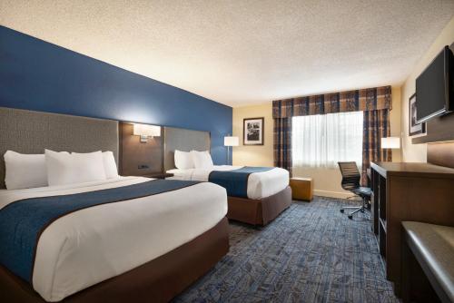 a hotel room with two beds and a television at Ramada by Wyndham Spokane Airport in Spokane