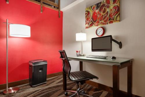 a desk with a computer in a room with a red wall at Ramada by Wyndham Spokane Airport in Spokane