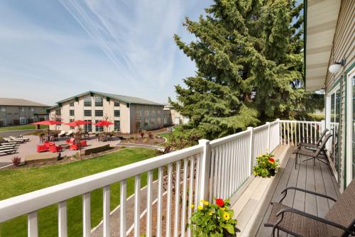 a balcony with tables and chairs and a yard at Ramada by Wyndham Spokane Airport in Spokane
