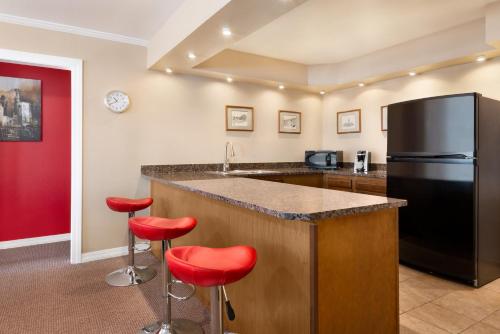 a kitchen with a black refrigerator and red stools at Ramada by Wyndham Spokane Airport in Spokane
