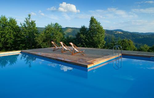 a pool with four chairs sitting on a wooden deck at Apartamenty Malinka in Wisła