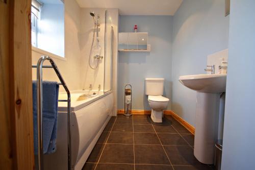a bathroom with a tub and a sink and a toilet at Aunt Rachel's Cottage in Bushmills