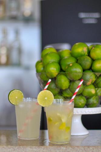 two glasses of lemonade on a table with a basket of limes at Simas Praia Hotel in Aracaju