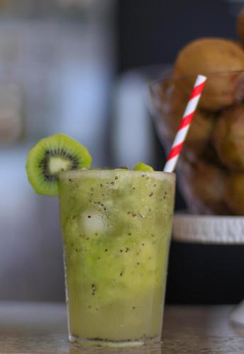a drink with a kiwi and a red and white straw at Simas Praia Hotel in Aracaju