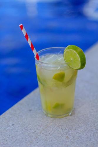 a drink with a lime and a red and white straw at Simas Praia Hotel in Aracaju