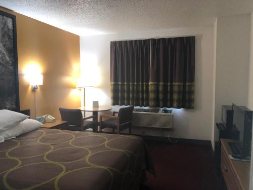 a hotel room with a bed and a table and chairs at Super 8 by Wyndham Front Royal in Front Royal