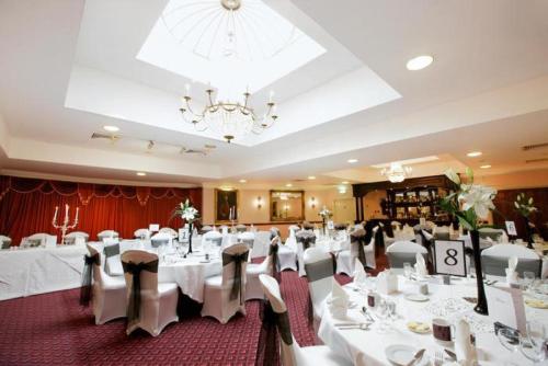 a banquet hall with white tables and chairs and a chandelier at Livermead House Hotel in Torquay