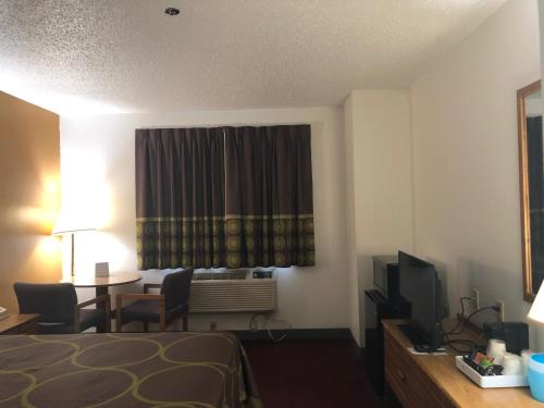 a hotel room with a bed and a desk with a television at Super 8 by Wyndham Front Royal in Front Royal