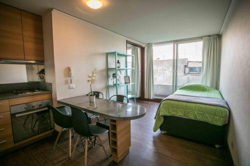 Cette petite chambre comprend un lit, une table et des chaises. dans l'établissement Apartments Zenteno, à Santiago