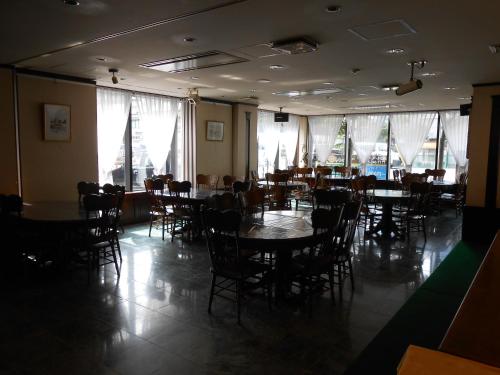 un comedor con mesas, sillas y ventanas en Terminal Art Inn en Niigata