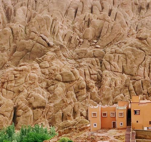 a rocky mountain with houses in front of it at Maison D'hote Chez La Famille in Tamellalt