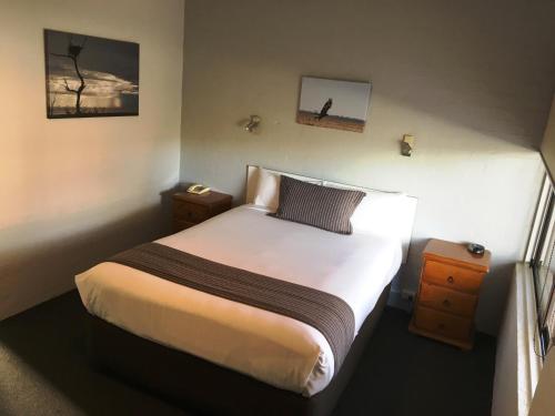 a bedroom with a bed and two nightstanduments sidx sidx sidx sidx at Nicholas Royal Motel - No Pets Allowed in Hay