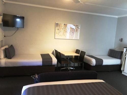 ein Hotelzimmer mit 2 Betten und einem Tisch in der Unterkunft Nicholas Royal Motel - No Pets Allowed in Hay