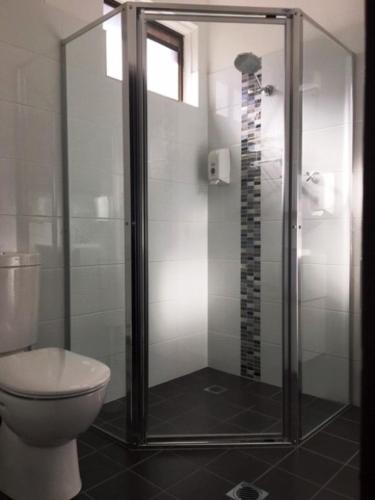 a bathroom with a toilet and a glass shower at Nicholas Royal Motel - No Pets Allowed in Hay