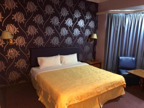 een slaapkamer met een bed en een muur met bloemen bij King Park Hotel Tawau in Tawau