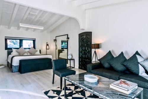 a bedroom with a bed and a couch and a table at Las Casas B&B Boutique Hotel, Spa & Restaurante Cuernavaca in Cuernavaca