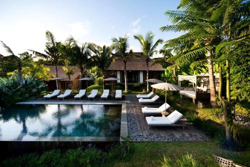 a resort with a pool with lounge chairs and umbrellas at Kalapa Boutique Resort & Yoga in Canggu