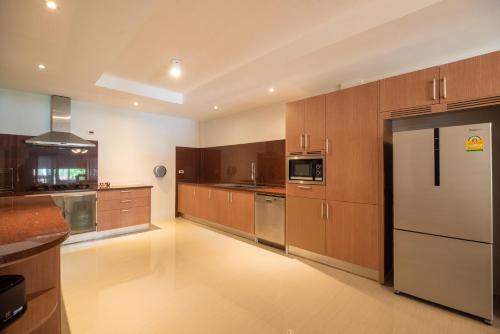 a large kitchen with wooden cabinets and stainless steel appliances at Wandee Garden in Choeng Mon Beach