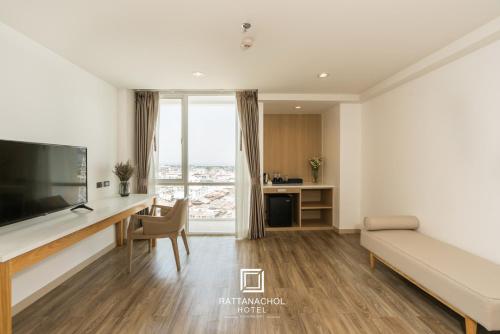 a hotel room with a desk and a large window at Rattanachol Hotel in Chon Buri
