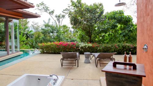 a backyard with a tub and chairs and a pool at Sri Panwa Phuket Luxury Pool Villa Hotel - SHA Plus in Panwa Beach