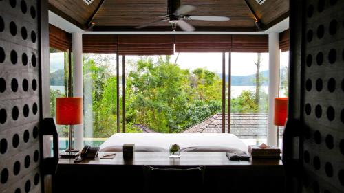 a bedroom with a bed and a large window at Sri Panwa Phuket Luxury Pool Villa Hotel - SHA Plus in Panwa Beach