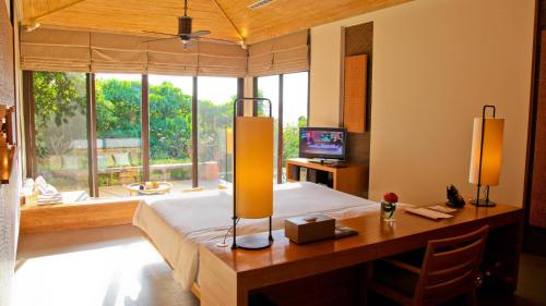 a bedroom with a bed and a desk and a window at Sri Panwa Phuket Luxury Pool Villa Hotel - SHA Plus in Panwa Beach
