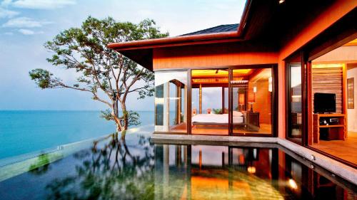 a house with a swimming pool next to the ocean at Sri Panwa Phuket Luxury Pool Villa Hotel - SHA Plus in Panwa Beach