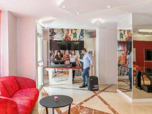 a man standing in a living room with his luggage at Mercure Paris Pont de Levallois Neuilly in Levallois-Perret